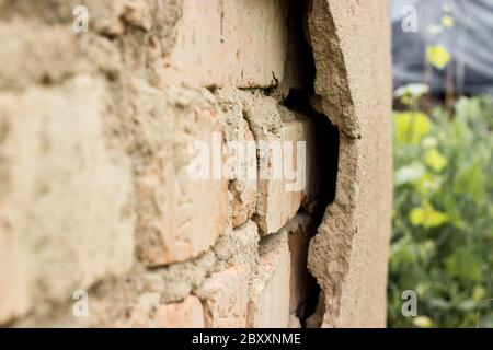 Non technology plaster. Building cracked plaster facade wall with brick. Stock Photo