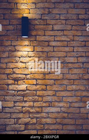 A section of a brown brick wall with an artificial light lamp. Stock Photo