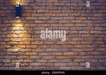 A section of a brown brick wall with an artificial light lamp. Stock Photo
