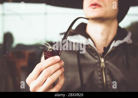 Close up view on smoking tabacco pipe in young man hand Stock Photo