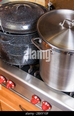 Blue canning kettle and large stainless steel stock pot being used to prepare apricot jam on a high-end stove Stock Photo