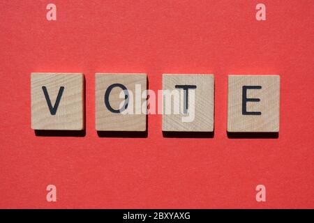 Vote, word in 3d wooden alphabet letters isolated on red background