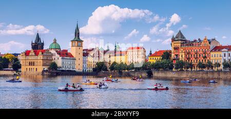 Scenic embankment in Prague city with paddle boats on Vltava river and Charles bridge; Historical center of Prague, buildings and landmarks of old tow Stock Photo