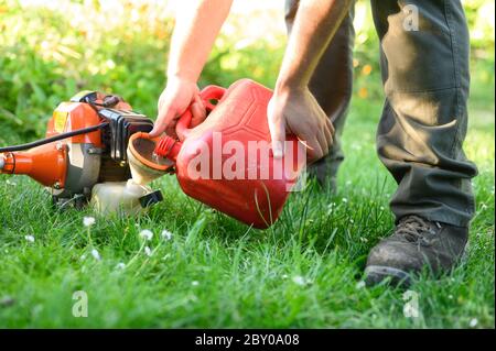 Gardener refueling brush cutter close up. Gardening tools