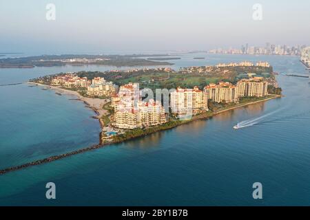 Aerial view of Fisher Island and Government Cut with City of Miami skyline and Port Miami in background at sunrise. Stock Photo