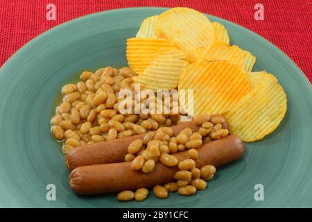 Meal of hot dogs and baked beans with flavored potato chips on blue plate Stock Photo