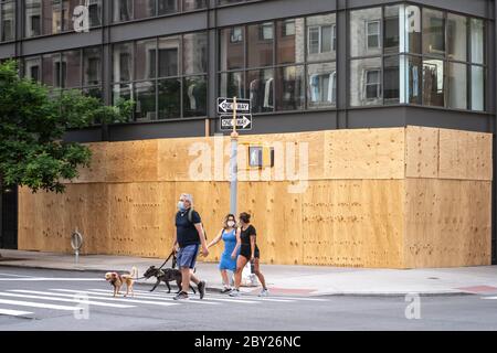 New York, USA. 8th June, 2020. Passers-by wear face masks as they walk by upscale stores protected with plywood in New York City's Madison Avenue. Many fancy shops kept their protections in case of rioting even as the city entered the first phase of reopening after the coronavirus lockdown. Credit: Enrique Shore/Alamy Live News Stock Photo