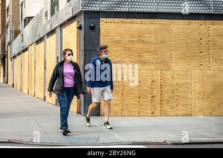 New York, USA. 8th June, 2020. Passers-by wear face masks as they walk by upscale stores protected with plywood in New York City's Madison Avenue. Many fancy shops kept their protections in case of rioting even as the city entered the first phase of reopening after the coronavirus lockdown. Credit: Enrique Shore/Alamy Live News Stock Photo