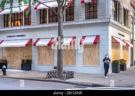 New York, USA. 8th June, 2020. Passers-by wear face masks as they walk by upscale stores protected with plywood in New York City's Madison Avenue. Many fancy shops kept their protections in case of rioting even as the city entered the first phase of reopening after the coronavirus lockdown. Credit: Enrique Shore/Alamy Live News Stock Photo