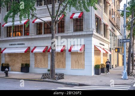 New York, USA. 8th June, 2020. Passers-by wear face masks as they walk by upscale stores protected with plywood in New York City's Madison Avenue. Many fancy shops kept their protections in case of rioting even as the city entered the first phase of reopening after the coronavirus lockdown. Credit: Enrique Shore/Alamy Live News Stock Photo