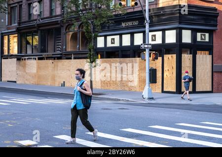 New York, USA. 8th June, 2020. Passers-by wear face masks as they walk by upscale stores protected with plywood in New York City's Madison Avenue. Many fancy shops kept their protections in case of rioting even as the city entered the first phase of reopening after the coronavirus lockdown. Credit: Enrique Shore/Alamy Live News Stock Photo