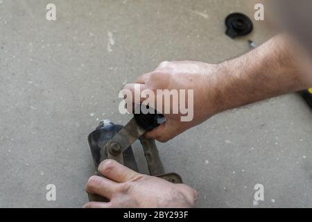 Auto mechanic works in the garage. Repairs. Disassembly of the trapezoid wiper. Diagnostics Stock Photo