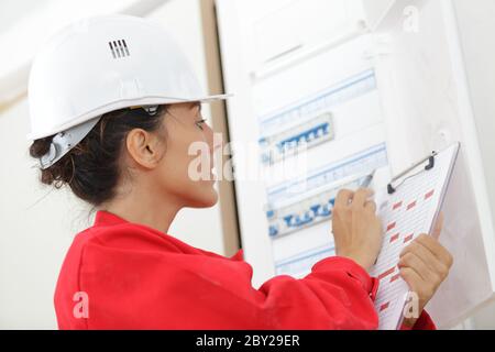 female worker inspecting fuse board Stock Photo