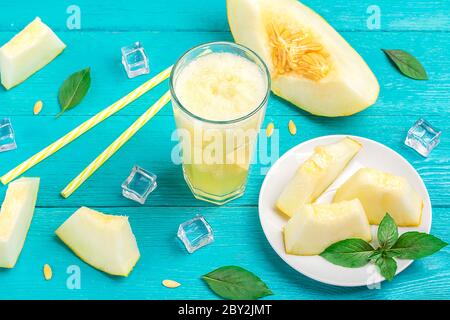 Melon lemonade, smoothie with ice and basil in a glass on blue wooden table. Summer refreshing and detox drink Rustic style Top view. Stock Photo