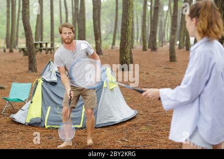 youg couple playing badminton by their tent Stock Photo