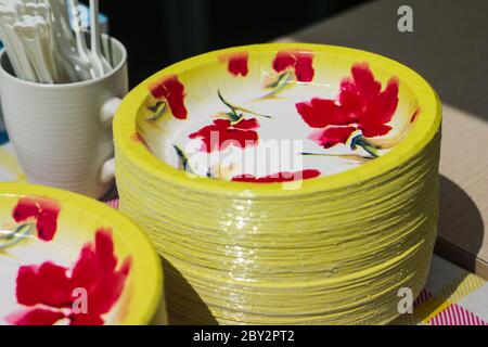 Flower pattern plate stacked and white mug on the table. Vibrant color of yellow plate with red flower pattern. Stock Photo