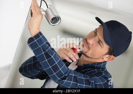 close-up of technician adjusting cctv camera on wall Stock Photo