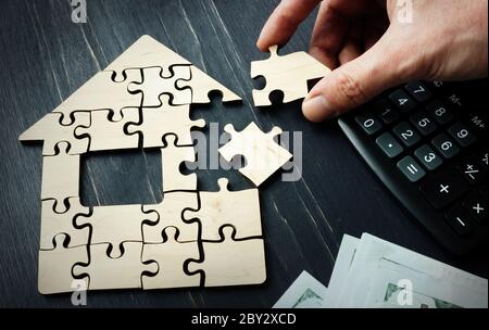 Savings on the purchase of real estate or a mortgage. A hand is collect a house from pieces of a puzzle. Stock Photo