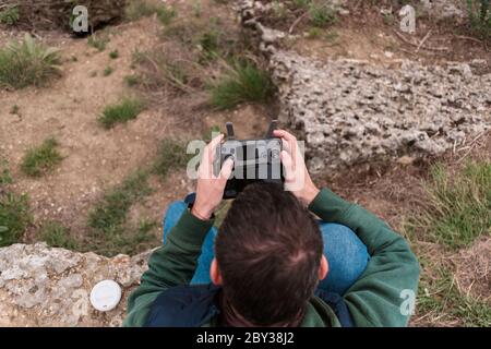 Young man piloting drone outdoor in nature. Guy testing aerial unmanned vehicle at nature. Backdrop for adult entertainment Stock Photo