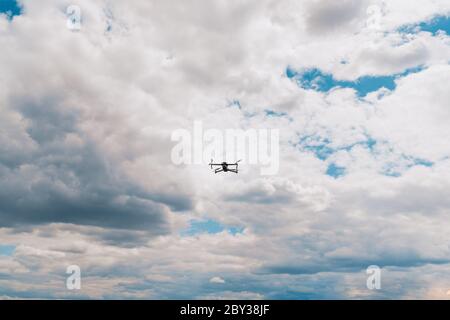 Drone flying overhead in cloudy blue sky Stock Photo