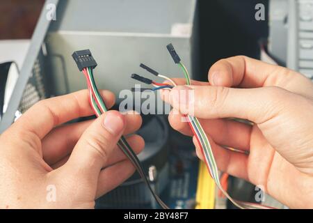 The repairer connects the wires in the computer. Repair and dismantling of computer equipment. Stock Photo