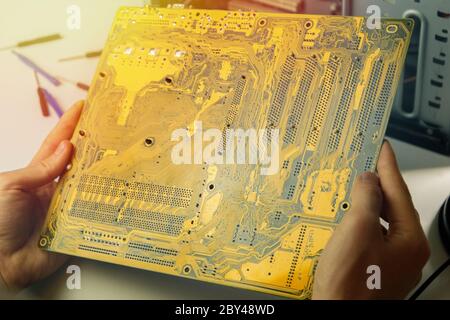 Computer repairman holds motherboard from computer in his hands. Professional PC repair Stock Photo