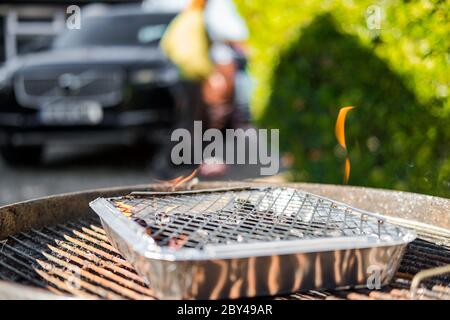Shallow focus of a camping bbq seen in a full size bbq. Flames can be seen being emitted, ready for meat to be cooked. Seen in a large garden. Stock Photo