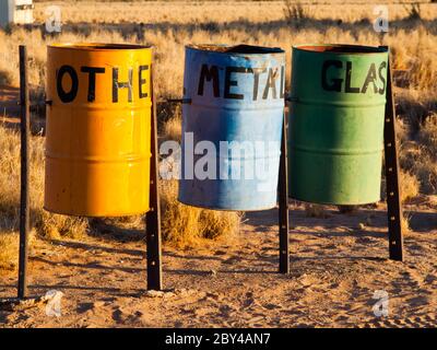 Three colorful recycle bins for metal, glass and other waste in the nature. Tin Barrels on at the camping site for waste separation. Stock Photo