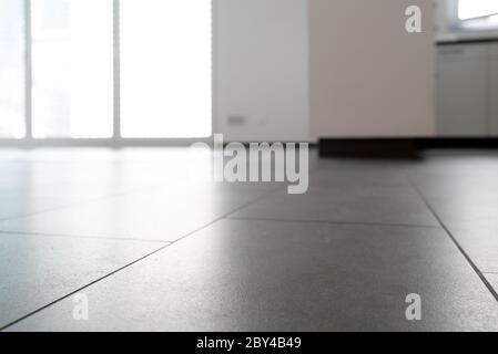 A low angle horizontal view of a new black ceramic tile floor in a bright white light apartment Stock Photo
