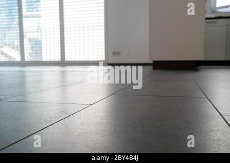 A low angle horizontal view of a new black ceramic tile floor in a bright white light apartment Stock Photo