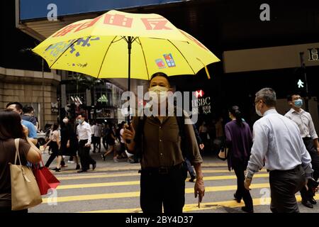 June 9, 2020, Hong Kong, CHINA: A lone protester hold up a YELLOW UMBRELLA, a symbol of Civil Disobedience of Hong Kongers, with a political slogan printed on it which reads : UPHOLD FREEDOM, AGAINST EVIL LAW walk across the road in the financial hub in Central. With 3 days to mark the first anniversary of Conflict which was fought over ANTI-EXTRADITION LAW last year by millions of Hong Kong citizens that lasted for 6 months, security in the financial centre are tightened to forbid citizens from demonstrating on the streets.June-9, 2020 Hong Kong.ZUMA/Liau Chung-ren (Credit Image: © Liau Chung Stock Photo