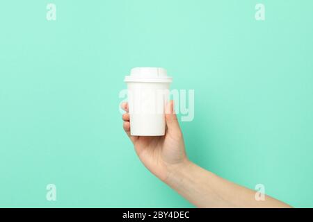Female hand holds paper cup on mint background, space for text Stock Photo