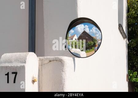 Newly installed blind spot mirror attached to the entrance of a house. Showing the reflection of the drive and garage. Stock Photo