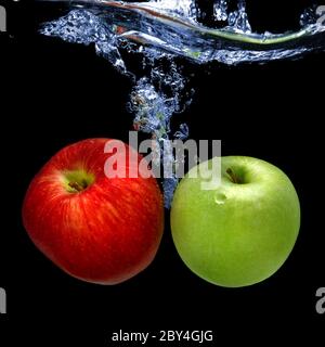 apples dropped into water with splash isolated on black Stock Photo