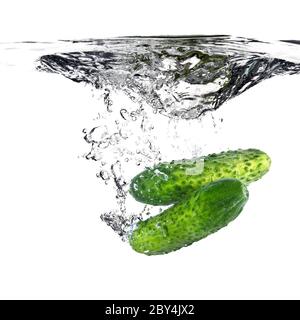 green cucumbers dropped into water isolated on white Stock Photo