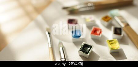 Plastic cells with watercolor paint and various brushes on a whi Stock Photo