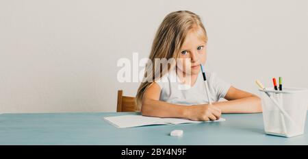 blonde girl sits at a table and writes in a notebook Stock Photo