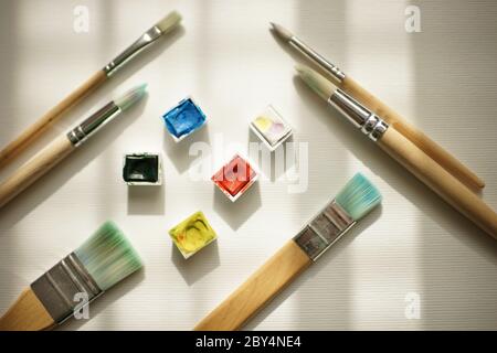 watercolor paint and different brushes on white paper. Stock Photo