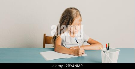 blonde girl sits at a table and writes in a notebook Stock Photo