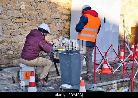 Limoux Aude France 12/10/19 Technicians working in the street installing fibre optic network for high speed internet network. Man operating a fibre co Stock Photo