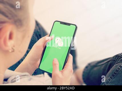 KYIV, UKRAINE-JANUARY, 2020: Wechat on Smart Phone Screen. Young Girl Pointing or Texting Wechat on Smartphone During a Pandemic Self-Isolation and Coronavirus Prevention. Stock Photo