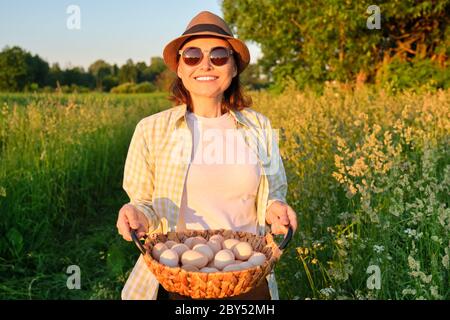 Portrait of farmer woman in hat with basket of fresh egg Stock Photo