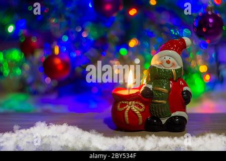 new year holiday background snowman in a hat with a candle on a wooden Board snow tree Christmas balls blurred background closeup Stock Photo