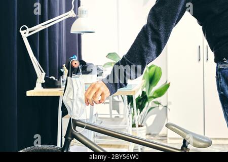 Man hanging his mask on the handlebars of his bike at the oofice Stock Photo