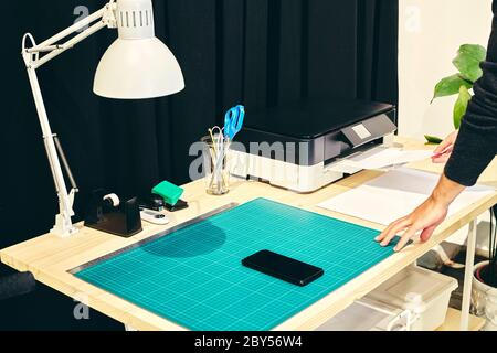 Office space with one person at the printer and a mobile phone on the table Stock Photo