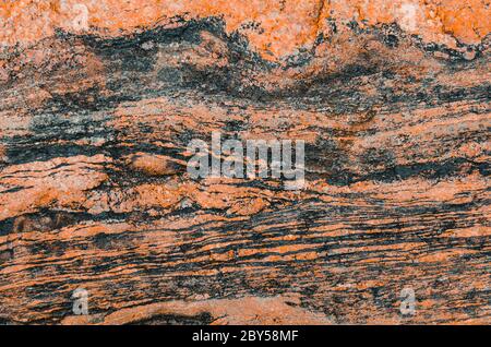 Wavy texture of granite stone red tint and dark stripes Stock Photo