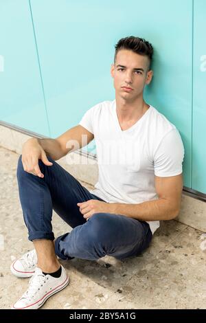 Young guy in depression sitting on ground street subway Stock Photo