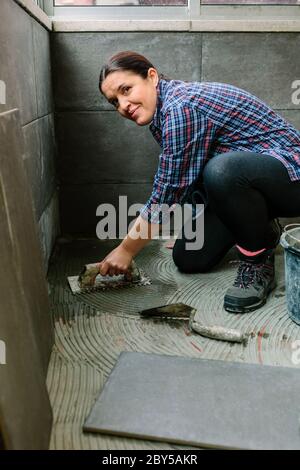 Female mason laying a new tile floor Stock Photo