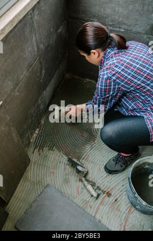 Female mason laying a new tile floor Stock Photo