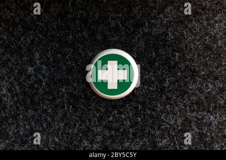 First Aid Kit and contents on a teak office desk, showing sticking plasters, pills and green box in background. Stock Photo